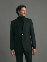 Traje de corte clásico compuesto por saco de dos botones y pantalón de vestir a juego. Diseño tradicional en color negro.