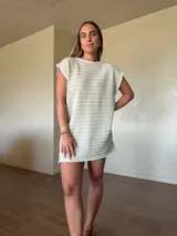 Vestido corto de tejido de punto en hilo de algodón y lurex color tostado con brillo, sin mangas y escote en la espalda.