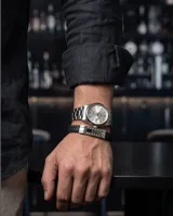 Pulsera de diseño masculino compuesta por una banda de cuerina trenzada negra y una pieza central de acero inoxidable con acabado pulido.