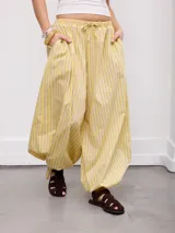 Pantalón palazzo amarillo con rayas verticales y diseño abombachado, cintura elástica con cordón de ajuste y bolsillos laterales.