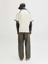 Camiseta tipo polo de manga corta con calce holgado, confeccionada en tejido liviano y flexible. Presenta cuello clásico, detalles en contraste y estampados gráficos en el frente con estilo deportivo.