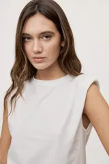 Remera sin mangas negra con cuello redondo y hombros estructurados con hombreras, de corte recto y largo a la cintura.