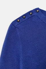 Jersey negro de punto de manga corta y cuello redondo, con detalle de botones dorados en el hombro.
