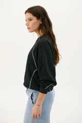 Buzo negro de corte cropped con mangas largas abullonadas y costuras a la vista en color blanco.