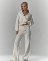 Conjunto de dos piezas de punto acanalado en color crema, compuesto por un sweater envolvente con escote en V y detalles de encaje en los bordes, y un pantalón de tiro alto con cintura elástica ancha y detalle de encaje en el ruedo.