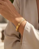 Pulsera tipo esclava rígida de acero con baño de oro, con diseño geométrico grabado en toda su superficie.