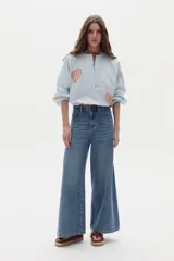 Pantalón de jean de pierna ancha y tiro alto, con bolsillos delanteros y traseros, presillas para cinturón y costuras verticales al frente.