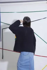 Sweater tejido de lana color negro con rayas horizontales en rojo, amarillo y verde. De corte holgado y mangas largas.