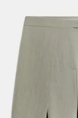 Pantalón de tiro alto con diseño tipo barrel, presenta pliegues frontales pronunciados, bolsillos laterales y cierre frontal con cremallera, botón interior y gancho metálico oculto.