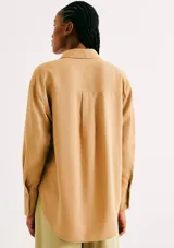 Camisa de manga larga con diseño extragrande y oversize, de color mostaza, con cuello clásico, cierre frontal con botones y bolsillo aplicado en el pecho.