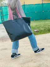 Bolso XL de cuero color marrón oscuro, con asas cortas de cuero y correa larga de tela estampada a rayas rojas y blancas.