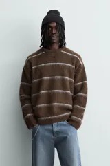 Jersey de punto con textura, corte relajado, cuello redondo y manga larga. Presenta un diseño de rayas horizontales en tonos marrones y grises con acabados en rib.