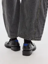 Mocasín plateado de cuero con punta cuadrada, detalle de estrella y talón en rojo.