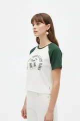 Remera al cuerpo con diseño raglán, color blanco en el torso y azul marino en las mangas cortas y el cuello. Cuenta con un estampado frontal de temática de tenis con las inscripciones "Portofino Tennis" y "Summer Italia".
