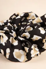 Gomita de pelo tipo scrunchie con estampado abstracto en negro, blanco y beige.