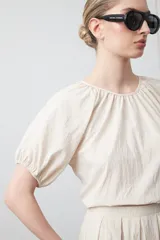 Top negro de manga corta con escote redondo y frunces en la costura de la sisa, creando un efecto de manga abullonada. El tejido parece ligero y con textura.