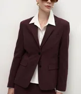 Blazer sastre de corte recto y estructura firme, color bordó con estampado de rayas de tiza. Presenta cuello con solapas definidas, cierre frontal con dos botones y mangas largas.