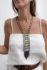 Collar largo de estilo boho con diseño de escalera, compuesto por dos cadenas metálicas oscuras unidas por barras horizontales de cuentas verdes y cubos dorados. Finaliza en un fleco de cadenas metálicas colgantes.