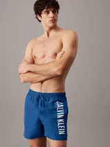 Short de baño de largo medio Calvin Klein, confeccionado en poliéster reciclado de secado rápido. Presenta cintura elástica con cordón ajustable, forro de malla interior, bolsillos laterales y un bolsillo trasero. Destaca por el logo de la marca estampado en vertical sobre la pierna.