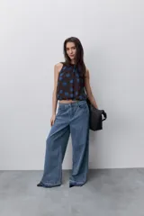 Jean de tiro alto y pierna wide leg, confeccionado en denim azul. Presenta diseño de cinco bolsillos, pasacintos, cierre frontal con botón y ruedo desflecado.