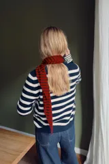 Chaqueta de punto con diseño de rayas horizontales en azul marino y blanco, cuello redondo, manga larga y cierre frontal con botones.