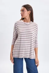 Remera de manga larga confeccionada en lanilla con diseño de rayas horizontales. Presenta cuello redondo y un corte holgado con caída fluida.