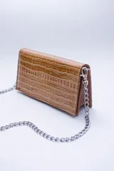 Cartera negra con textura símil cocodrilo y cadena metálica plateada.