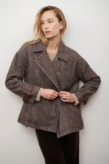 Chaquetón de lana color bordó con diseño de espiga y motas blancas. Tiene solapa, doble abotonadura frontal, mangas largas con detalle de correa y hebilla en los puños.