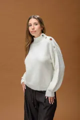 Polera de punto color blanco, de corte relajado y cuello alto. Presenta detalle de botones joya decorativos en uno de los hombros.