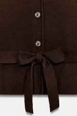 Chaqueta marrón de punto con cuello redondo y manga corta. Presenta cierre frontal con botones y un cinturón integrado del mismo tejido con lazo para atar en la cintura.