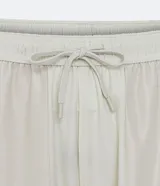 Bermuda deportiva color gris claro, con cintura elástica ajustable con cordón, bolsillos laterales y detalle de lettering reflectante en el lateral.