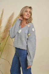Buzo de punto color gris, con cuello en V, mangas largas y detalles de flores tejidas en varios colores en el frente.