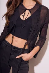 Blusa negra traslúcida de viscosa con textura arrugada, mangas largas acampanadas y escote en V con lazos.