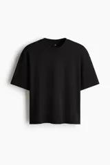 Remera boxy de algodón en punto liviano, de color negro con hombros caídos, cuello redondo acanalado y corte oversized para una silueta extraholgada.