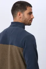 Campera polar bicolor de diseño texturado suave al tacto, con cuello alto, cierre frontal completo y bolsillos laterales. Presenta una combinación de color azul marino en la parte superior y marrón en la inferior, con un pequeño logo bordado en el pecho.