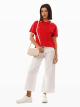 Cartera bandolera Tommy Hilfiger con estampado del monograma TH en tonos beige y rosa. Tiene correa ajustable, cierre con solapa, bolsillo interior con cremallera y logo metalizado TH en la parte delantera.