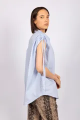 Camisa sin mangas color verde esmeralda, con cuello clásico, cierre frontal con botones y tiras regulables en los hombros.