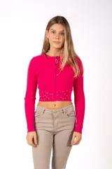 Campera de punto acanalado color fucsia, de corte cropped y manga larga. Presenta cierre frontal con tirador decorativo y detalle de tachas metálicas circulares en la parte inferior.