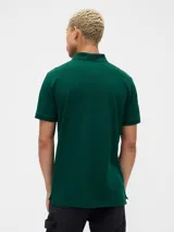 Polo de manga corta color verde oscuro, con cuello clásico, cierre frontal de dos botones y logo del oso Brannan bordado en el pecho.