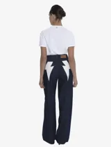 Pantalón de jean ancho (wide leg) de tiro medio, color azul oscuro, con cierre frontal de botón y cremallera, y un detalle de cierre funcional en la parte posterior.