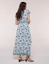 Vestido maxi de rayón con estampado floral en tonos azules y marrones sobre base blanca, con escote en V, mangas cortas y falda larga fluida con volado en el ruedo.