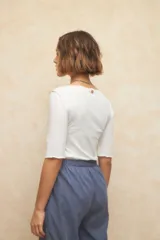 Remera negra de manga tres cuartos, escote redondo y detalle de costuras superpuestas de forma asimétrica.