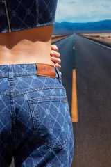 Jean de tiro bajo y corte oversize, confeccionado en denim azul con grabado láser de monograma en patrón de rombos. Presenta avíos metálicos y diseño de pierna ancha.