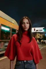 Jersey de punto liso en color gris, con cuello subido y mangas anchas de corte holgado. Presenta acabados en rib en el cuello y los puños.