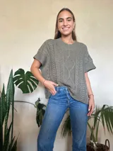 Chaleco tejido color verde oliva, con cuello en v y diseño de trenzas y ochos. Silueta oversize.