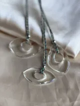 Gargantilla con tiento trenzado y dije abstracto de resina transparente.