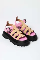 Sandalia tipo gladiadora con plataforma track negra. Presenta un diseño bicolor con tiras delanteras en color amarillo neón y talón con tira ajustable en color beige. Incluye hebilla metálica negra.