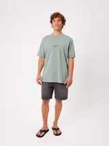 Remera blanca Rusty de corte holgado, con cuello redondo y mangas cortas. Presenta un estampado en la espalda de estilo veraniego con palmeras, una tabla de surf y letras alusivas a la marca.