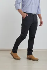 Pantalón de vestir verde oliva, de corte slim fit, sin pinzas, con bolsillos laterales y traseros. Se ajusta a la cintura con cinturón de cuero marrón.