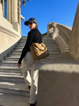 Bolso tipo shopper negro de lona, con bolsillo frontal con cierre y correa bandolera ajustable y desmontable.